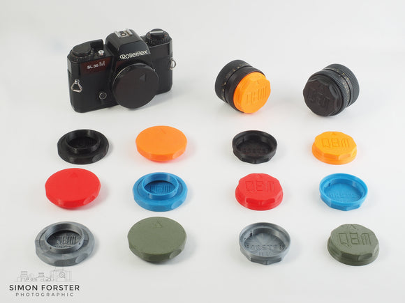 A collection of fifteen caps which are designed to fit Rollei QBM lenses and Rolleiflex cameras. Seven of the caps are body caps which fit the camera body of a Rolleiflex camera. Eight of the caps are rear lens caps designed to fit the rear element of all Rollei QBM mount lenses. The caps are being displayed in a plain white background.