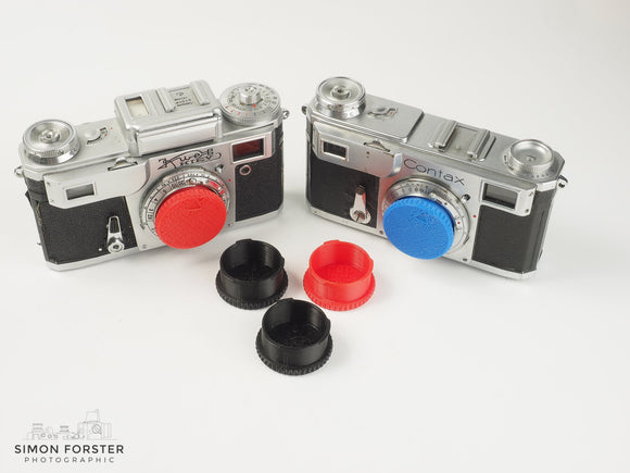 Five individual body caps which have been designed to fit contax and kiev camera body's, are being showcased in plain white background read for sale. Two of the body caps are black, two are red and one is light blue.