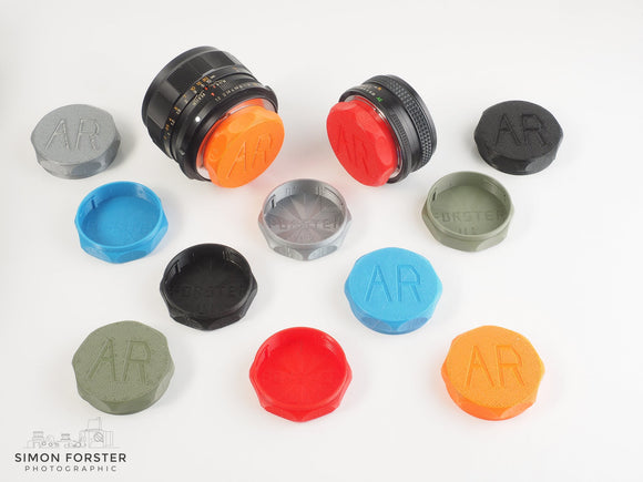 Rear lens caps designed for Konica AR mount rear lenses in black orange red light blue silver military green being displayed on a plain white background