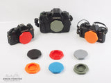 Assorted Forster UK Contax/Yashica body caps in various colours for Contax/Yashica mount cameras on a white backdrop.