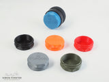 Six rear lens caps which have been designed to fit HI topcor lenses are being displayed on a plain white background including a HI topcor lens which has a mid blue cap mounted onto its rear element. The other caps are being showcase in front of the lens and mid blue cap. These caps are in black, orange, red, silver and survival green.