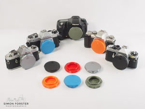 Assorted 3D-printed PK mount rear lens caps and body caps in various colours for Pentax K mount cameras and lenses by Forster UK.